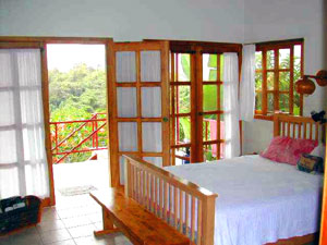 The master bedroom has a windowed wall and doors that give views of Lake Arenal.